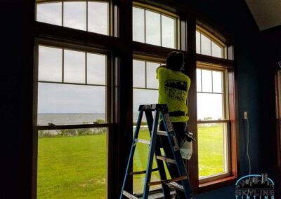 installer tinting large home windows overlooking water