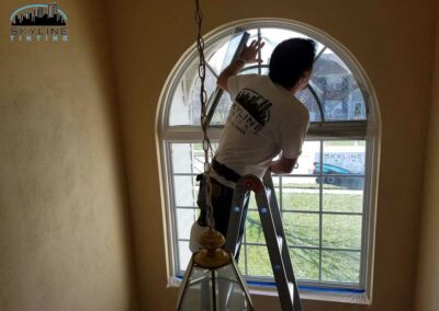 installer on ladder tinting a two piece residential foyer window