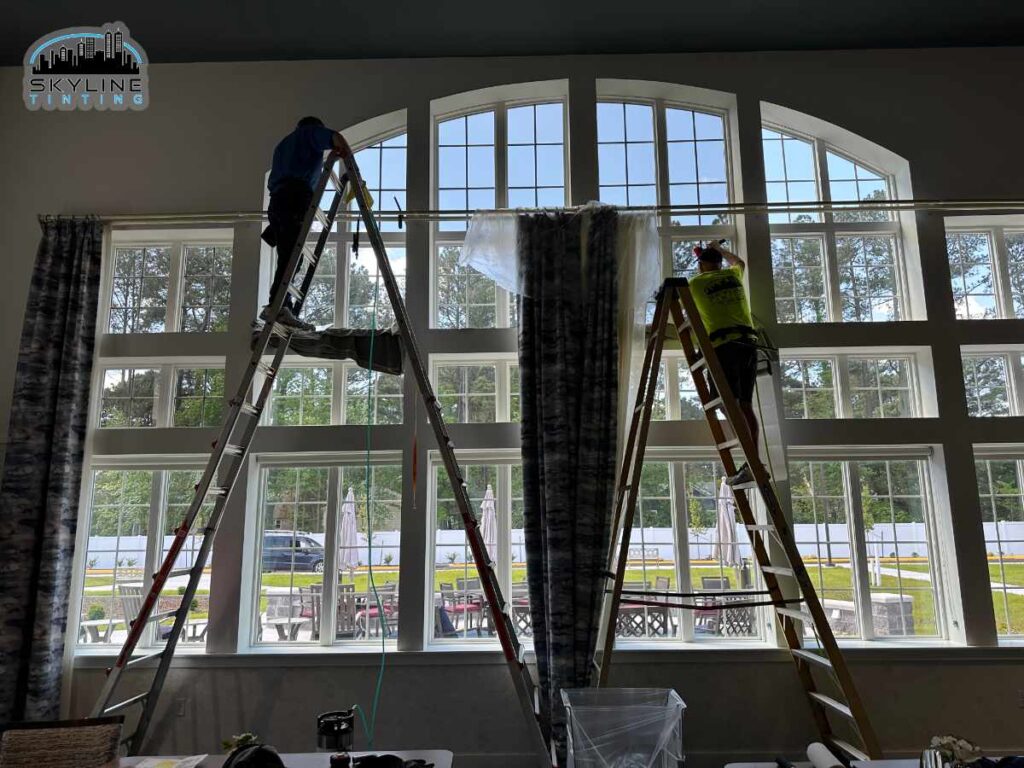 interior view of two tint installers on ladders working on large window unit