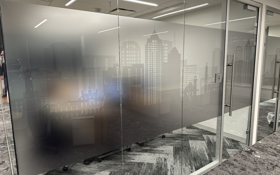 Frosted glass office partition with a city skyline design in a modern corporate hallway.