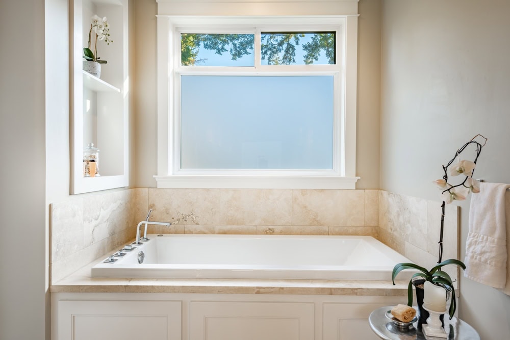 three piece window unit above a home tub viewed from the inside with the lower pane of glass having frosted window film installed to obscure vision