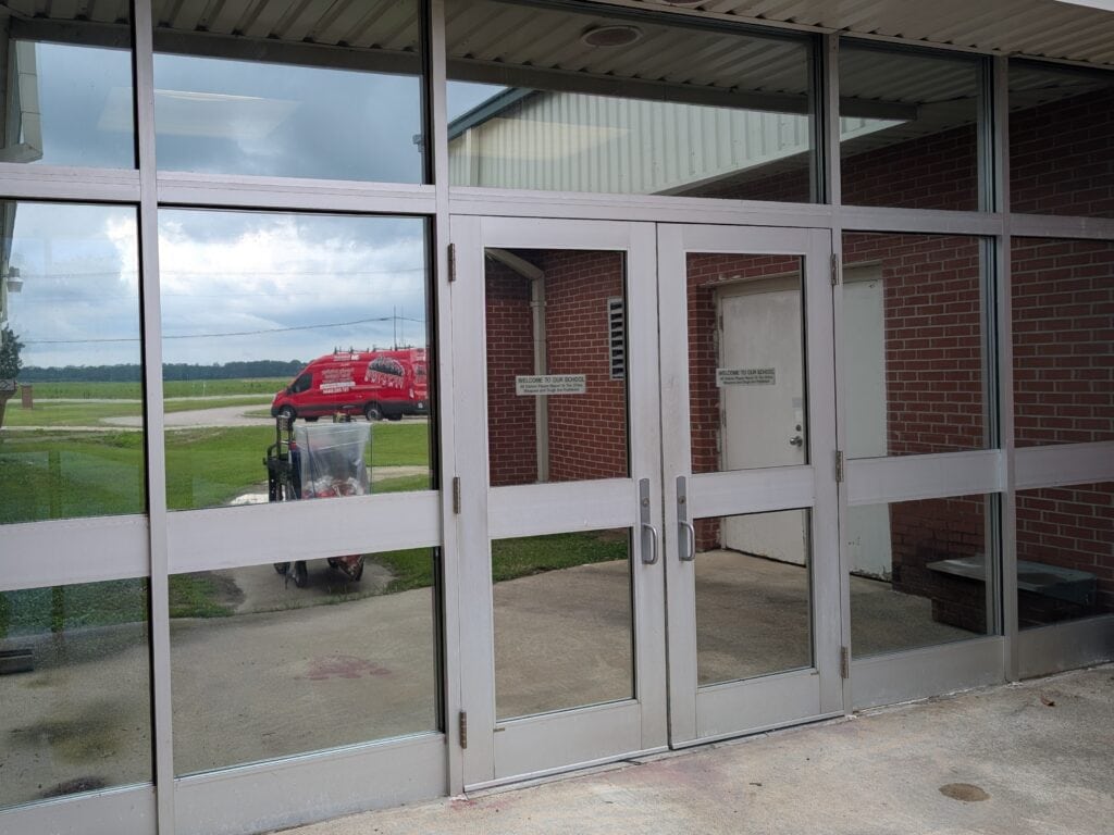 exterior view of silver metal commercial entryway with reflective security window film installed